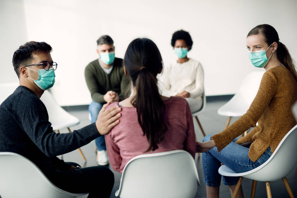 Group of people wearing face masks while participating in psychotherapy during coronavirus pandemic.  - Фото, изображение