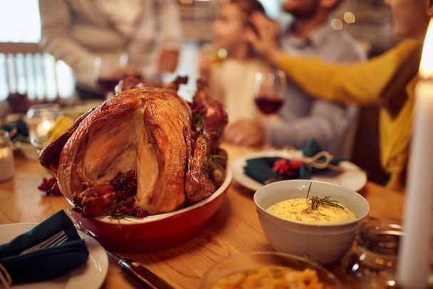 Close-up of Thanksgiving turkey on dining table with family in the background,  - Fotoğraf, Görsel