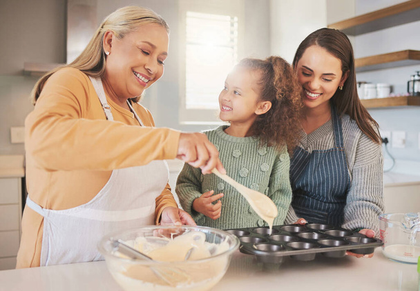 een klein meisje bakken met haar moeder en grootmoeder thuis. - Foto, afbeelding