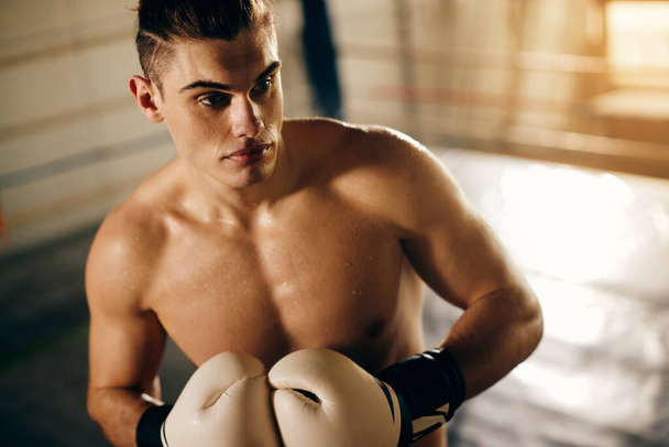 Mladý svalnatý bojovník s boxerskými rukavicemi připravený na sportovní trénink v boxerském klubu.  - Fotografie, Obrázek