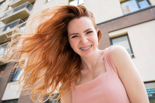 Beautiful young red-haired woman with braces on her teeth smiling in the summer outdoors. - Φωτογραφία, εικόνα