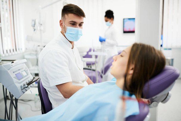 Male dentist talking to female patient before dental procedure at dental clinic.  - Photo, Image