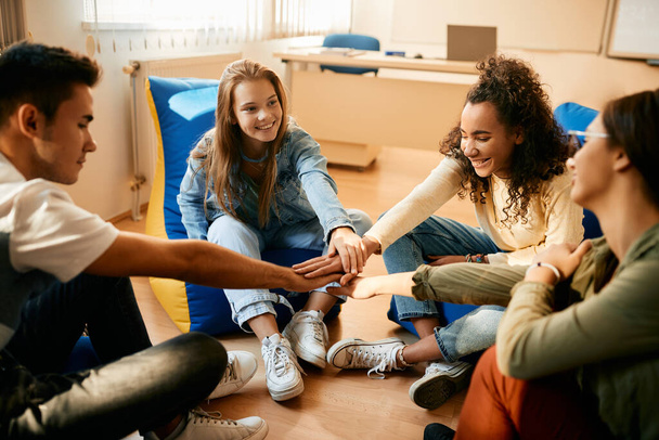 Multiracial group of teenagers uniting hands while celebrating their friendship in the classroom. - Fotoğraf, Görsel