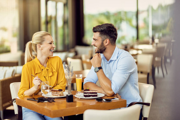 Щаслива пара розважається під час їжі торта і спілкування в кафе
.  - Фото, зображення
