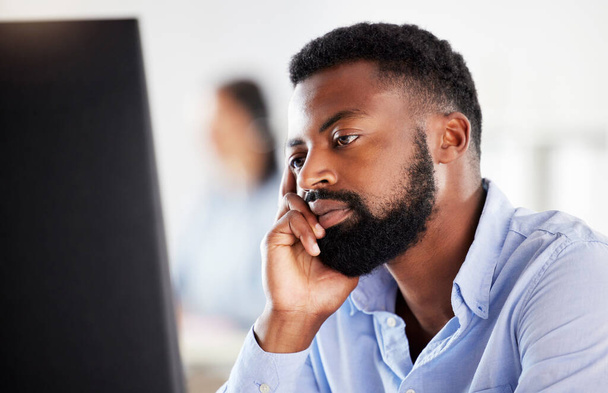 One exhausted african american businessman looking bored while working on computer in an office. Guy feeling overworked, tired and demotivated. Lazy employee slacking and ignoring deadlines. Burnout - Foto, Imagen