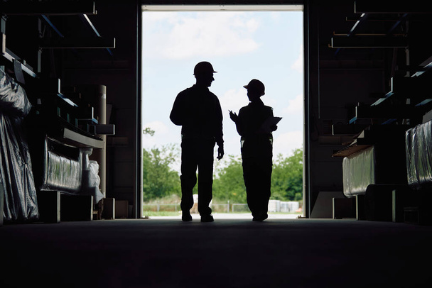 Silhouette of workers communicating at distribution warehouse. Copy space. - 写真・画像