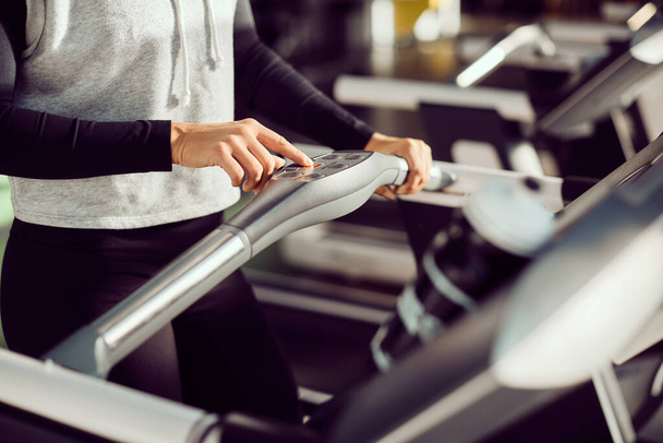 Close-up of athletic woman pressing start button while exercising on treadmill at health club. - Foto, imagen