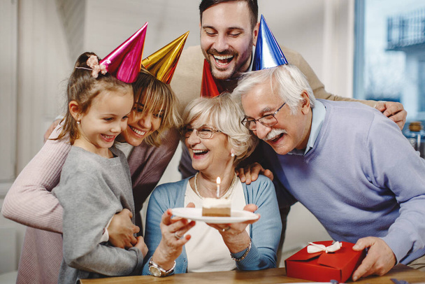 Χαρούμενη οικογένεια πολλών γενεών που διασκεδάζει ενώ γιορτάζει τα γενέθλια της ηλικιωμένης γυναίκας στο σπίτι.  - Φωτογραφία, εικόνα