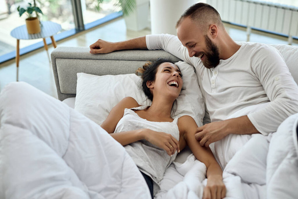 Високий кут зору щасливої пари розважається під час відпочинку на ліжку і розмовляє
.  - Фото, зображення