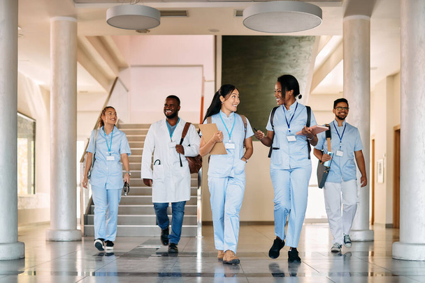 Happy multiracial medical students talking while walking through corridor of medical university. - Foto, imagen