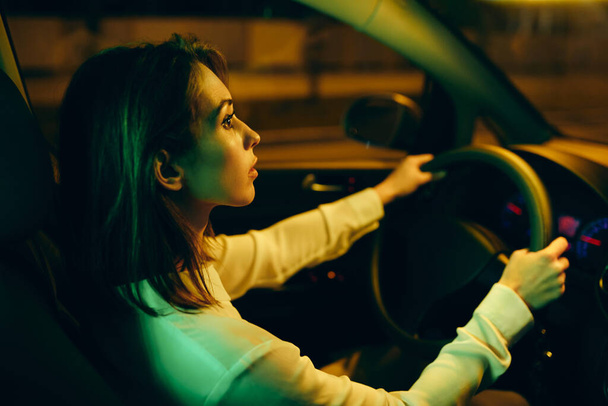 Молода жінка їде сама в машині вночі
.  - Фото, зображення