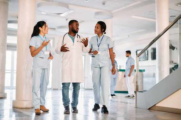 Multiracial group of medical students talking while through a corridor at university hospital.  - Foto, Imagem