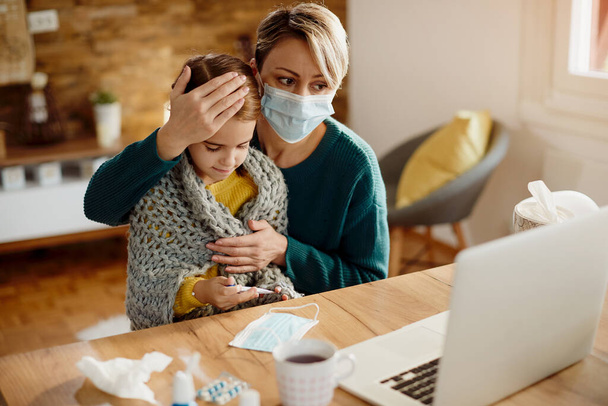 Single mother having video call with a doctor while her daughter is having high fever during coronavirus pandemic.  - Valokuva, kuva