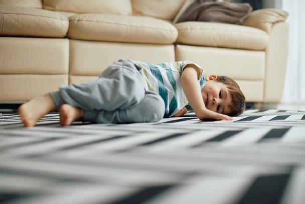 Smiling little boy relaxing on the floor at home and looking at camera.  - Foto, imagen