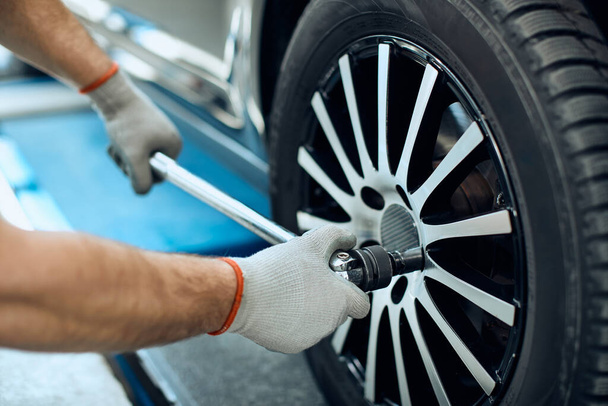 Close-up of mechanic changing car tire at auto repair shop.  - Photo, Image