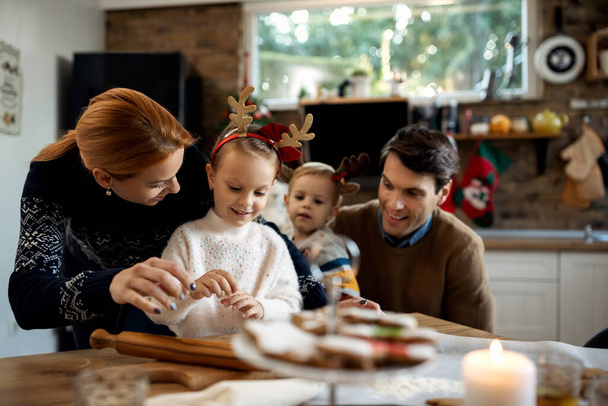 Boldog család szórakozik, miközben sütit süt karácsonyra a konyhában. Koncentrálj anyára és lányára..  - Fotó, kép