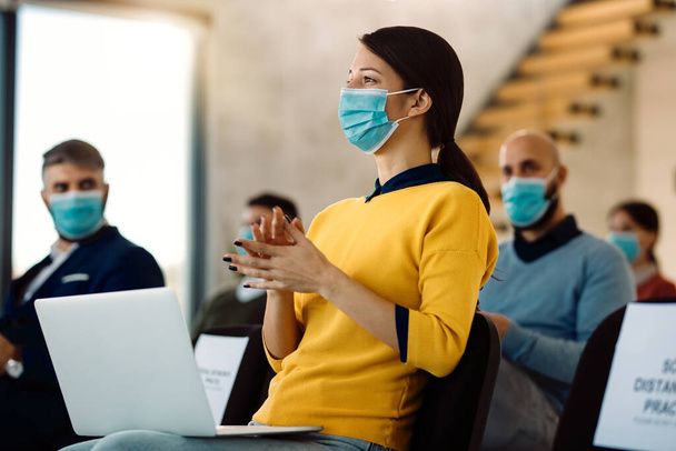Group of business people with face masks applauding after successful conference in board room. Focus is on a businesswoman in foreground.  - Foto, Imagen