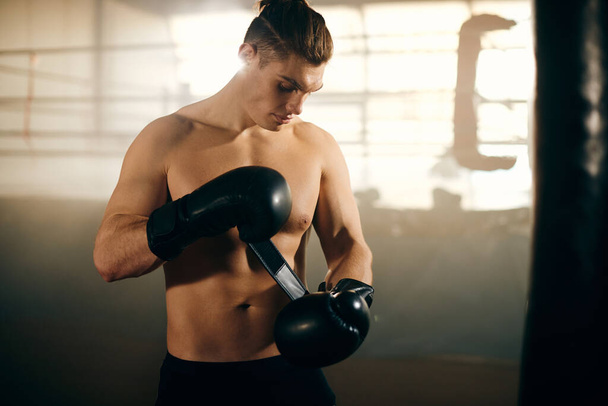 Молодий боєць налаштував свої боксерські рукавички під час роботи в спортзалі
.  - Фото, зображення
