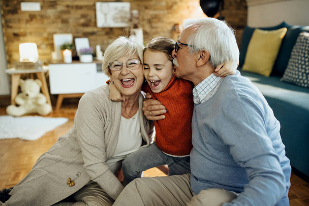Cheerful little girl having fun and embracing her grandparents at home.  - Foto, immagini