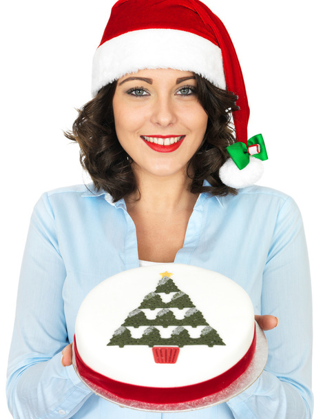 Νεαρή γυναίκα με το καπέλο Santa κρατώντας ένα χριστουγεννιάτικο κέικ φρούτων - Φωτογραφία, εικόνα
