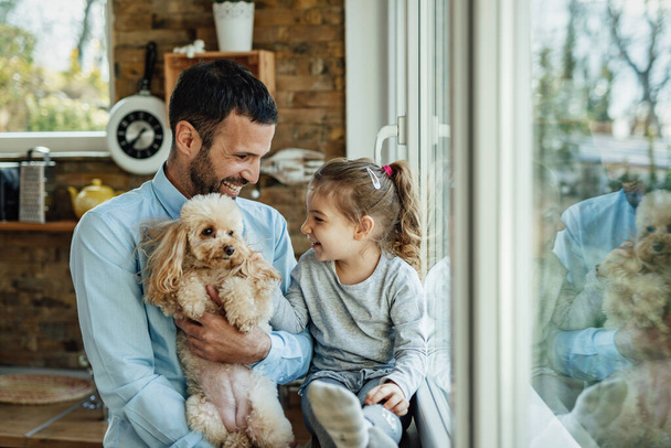 Happy little girl and her father enjoying with their dog at home.   - Photo, image