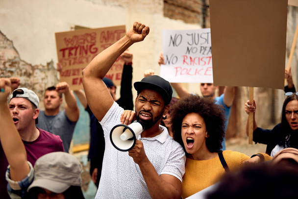 Неймовірна чорна пара кричить під час маршу з групою людей на знак протесту проти расизму
. - Фото, зображення