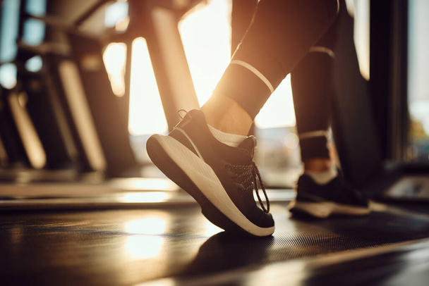Close-up of athletic woman warming up for sports training while walking on treadmill in a gym. - Foto, Imagem