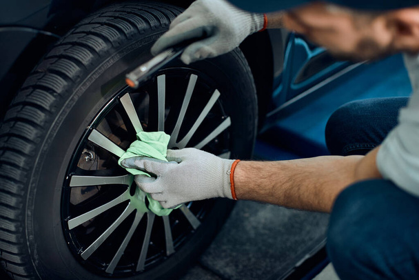 Close-up of mechanic cleaning car tire after changing it at auto repair shop. - Фото, зображення