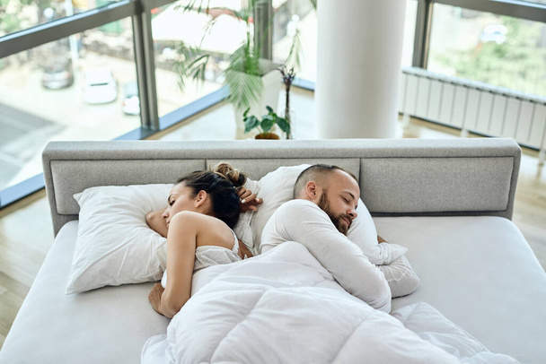 High angle view of a couple sleeping back to back on a bed.  - Foto, imagen
