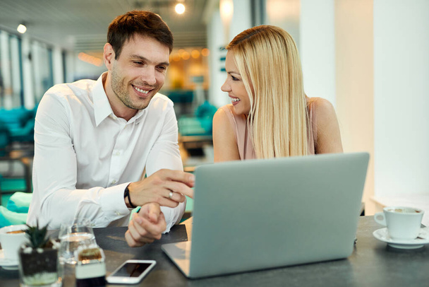 Ευτυχισμένο ζευγάρι επιχειρήσεων που εργάζονται σε έναν υπολογιστή, ενώ κάθεται σε ένα καφέ.  - Φωτογραφία, εικόνα