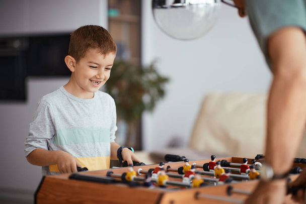 Small boy having fun with his grandfather while playing foosball together at home. - Zdjęcie, obraz