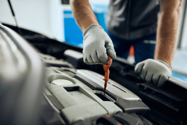 Close-up of auto repairman checking car oil in a workshop.  - Foto, afbeelding
