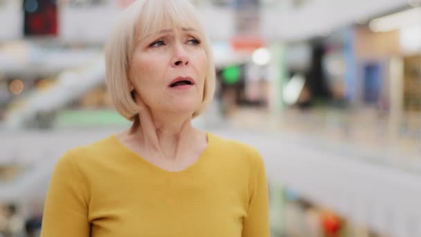 Mature caucasian unwell woman standing indoors coughing covers mouth with hands elderly unhealthy female suffering from flu symptoms colds chronic asthma disease feels choking first symptom of virus - Footage, Video
