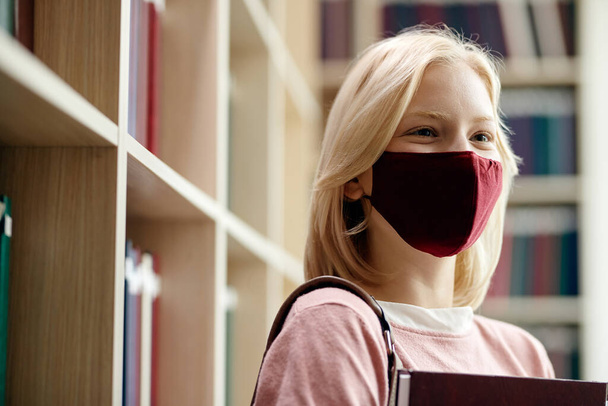 Happy female student with protective face mask in library at the university.  - Fotoğraf, Görsel
