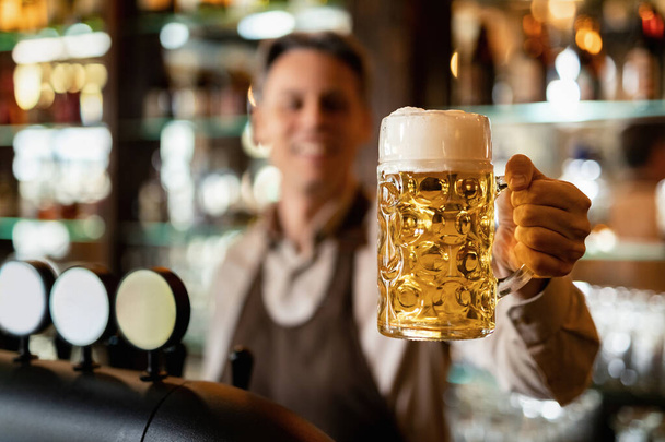 Close-up of barista holding glass of craft beer in a bar.  - Фото, зображення