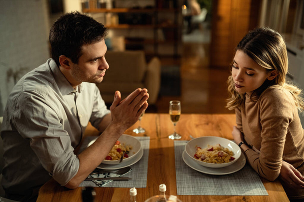 Young woman feeling sad while her boyfriend is trying to apologize during dinner at dining table.  - Φωτογραφία, εικόνα