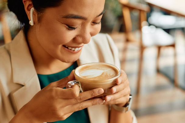 Young Asian businesswoman having cup of latte coffee during her break.  - 写真・画像