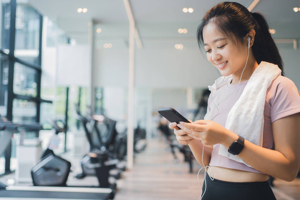 Athletic girl using smartphone in a gym, lifestyle and healthy concept. - 写真・画像