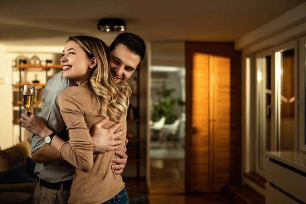 Happy couple in love standing embraced in the living room at night.  - Foto, imagen