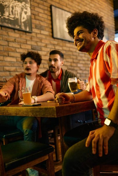 Multiracial group of sports fans watching a match on TV in a pub. Focus is on Muslim man.  - Foto, imagen