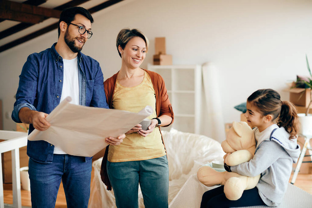 Happy family communicating while examining housing plans after relocating into a new home.  - Foto, Imagem