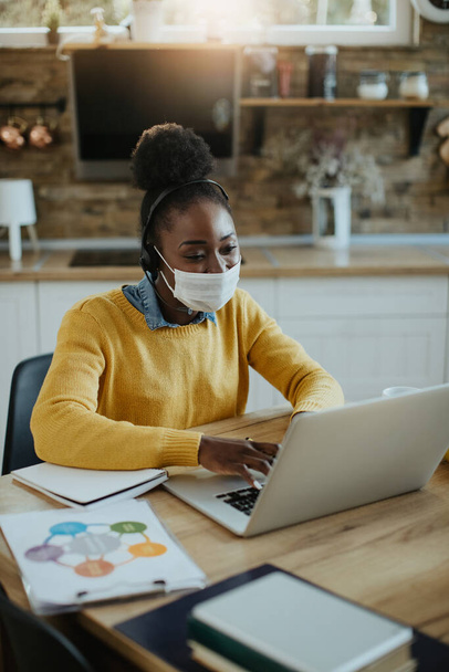 Happy African American freelance worker using computer while working at home during COVID-19 pandemic.  - Φωτογραφία, εικόνα