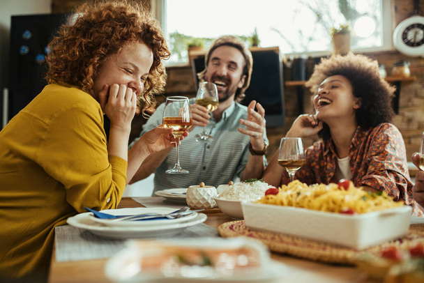 Young happy woman and her friends having fun while drinking wine during lunch time at home.  - Photo, Image