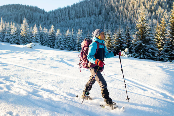 Μια γυναίκα περπατά με χιονοπέδιλα στο χιόνι, χειμερινή πεζοπορία, ένα άτομο στα βουνά το χειμώνα, εξοπλισμό πεζοπορίας - Φωτογραφία, εικόνα