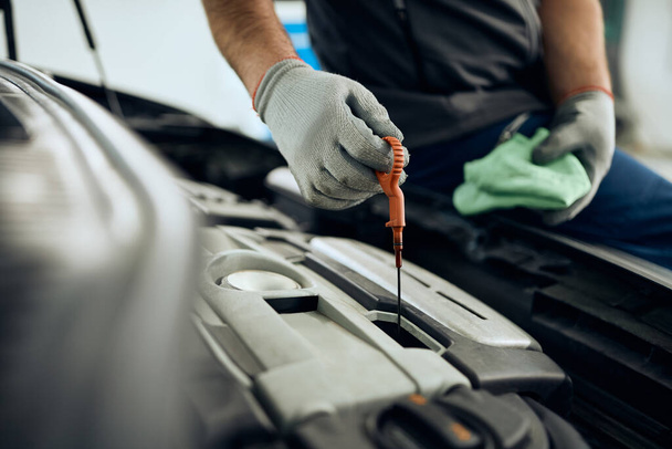 Close-up of car mechanic checking motor oil at auto repair shop. - Zdjęcie, obraz