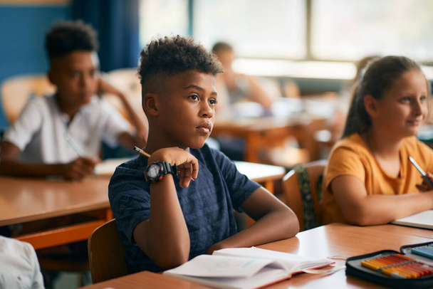 Афроамериканский школьник и его одноклассники обращают внимание во время занятий в классе.  - Фото, изображение