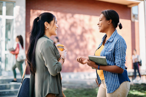 Happy Asian university student talking to her African American friend at campus. - Foto, Imagem