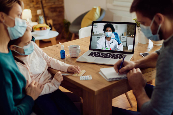 Close-up of parents with daughter talking to family doctor via video call from home during coronavirus pandemic.  - Фото, зображення