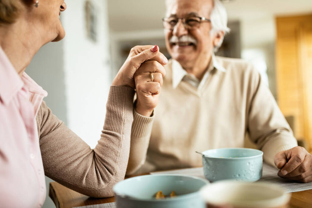 Close-up of happy senior couple holding hands while talking at dining table.  - Photo, image
