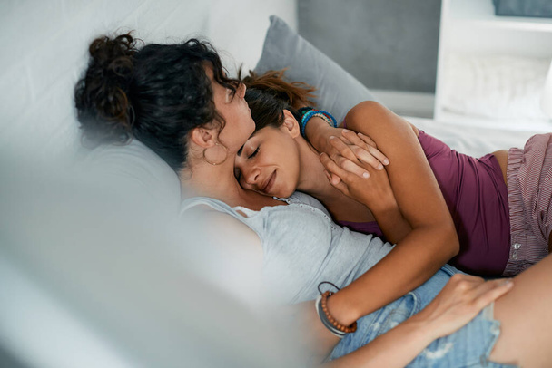 Young lesbian women in love embracing while lying don on bed at home.  - Foto, afbeelding